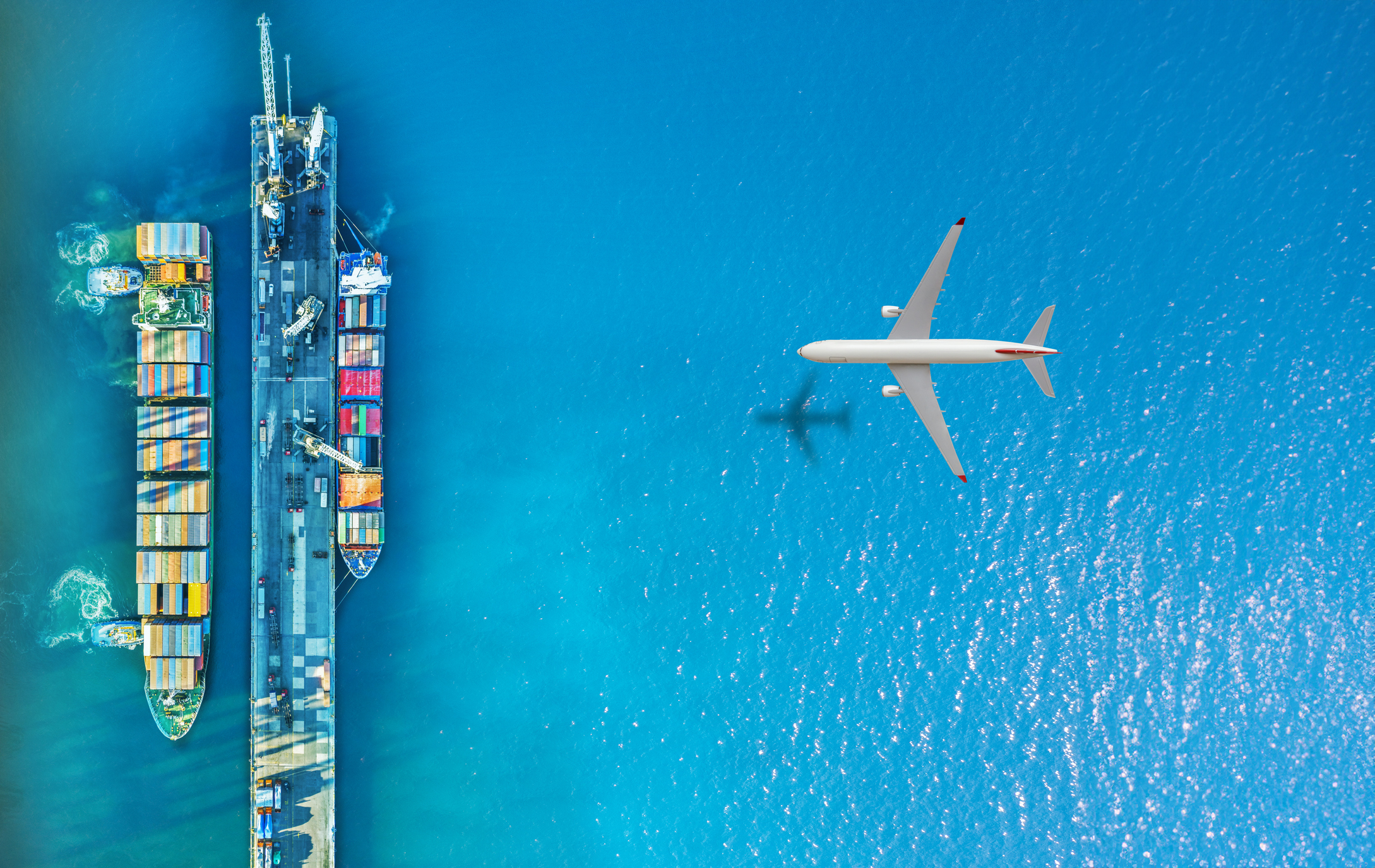 Cargo Airplane flying above container ship. Certified international chemical logistics in action, with specialty chemical containers prepared for global shipment by Qemi International.